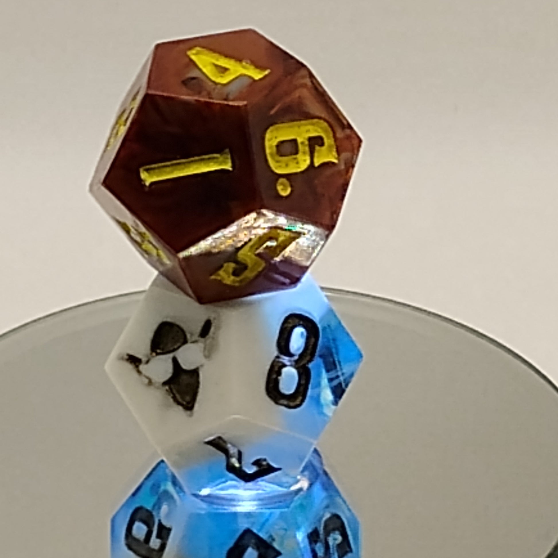 Two polyhedral dice, one brown and one clear with black numbers, on a white surface.