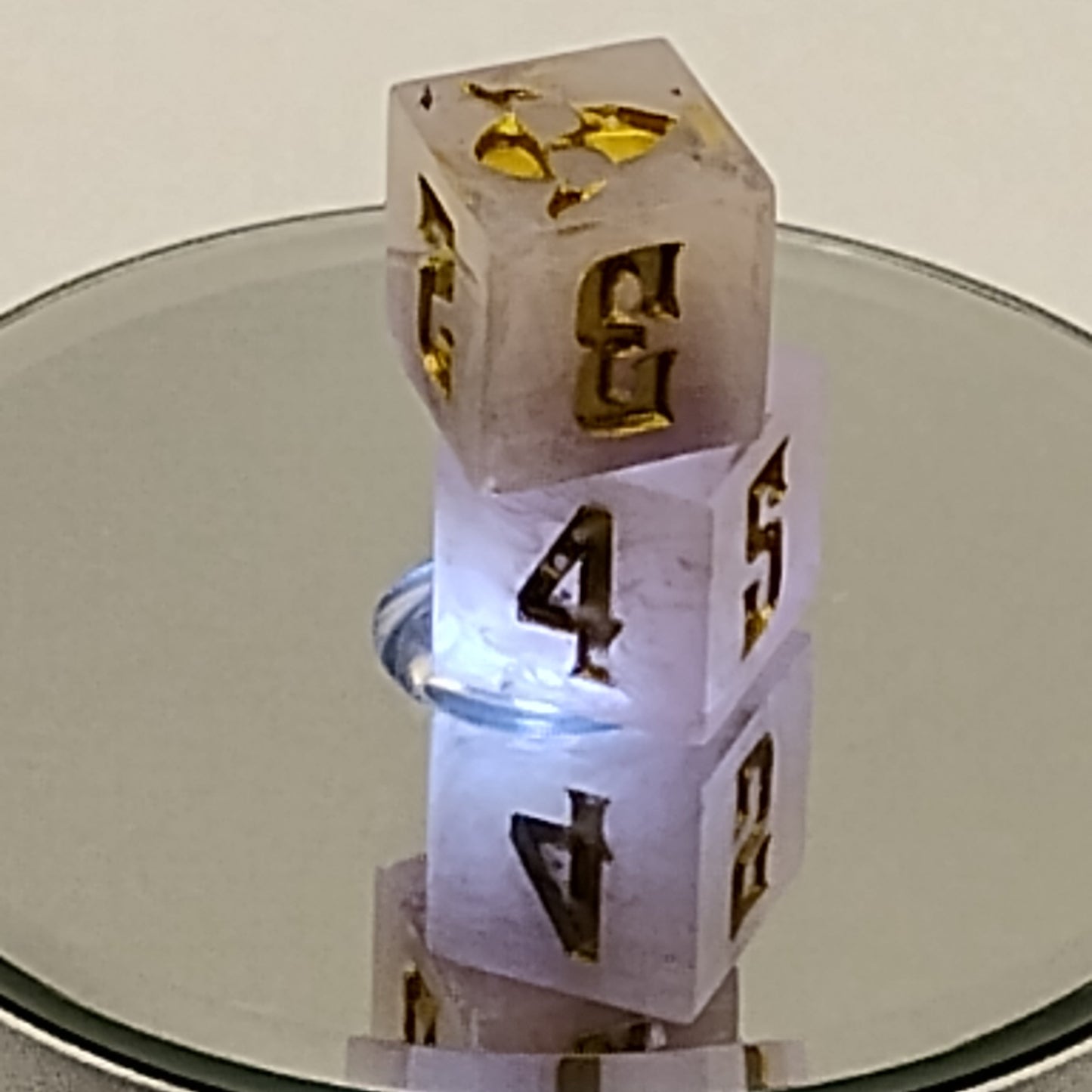 Transparent dice with gold and black numbers on a reflective surface