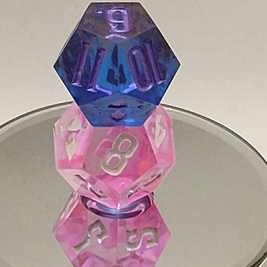 Two pink and blue dice with numbers on a mirror background