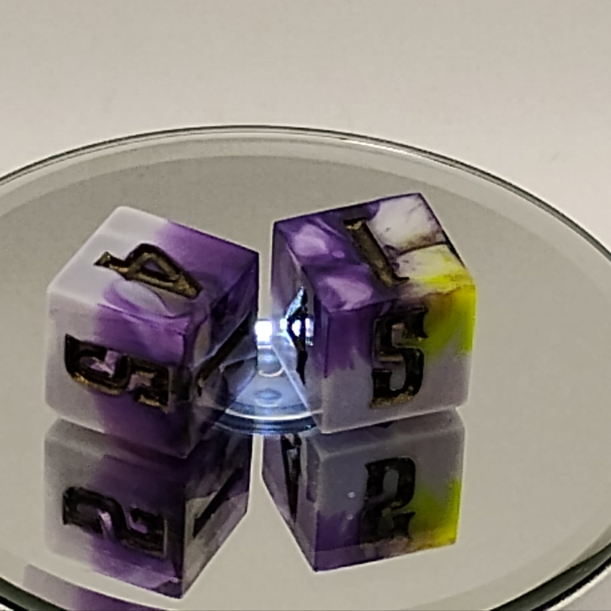 Close-up of a purple and green die set on a reflective surface