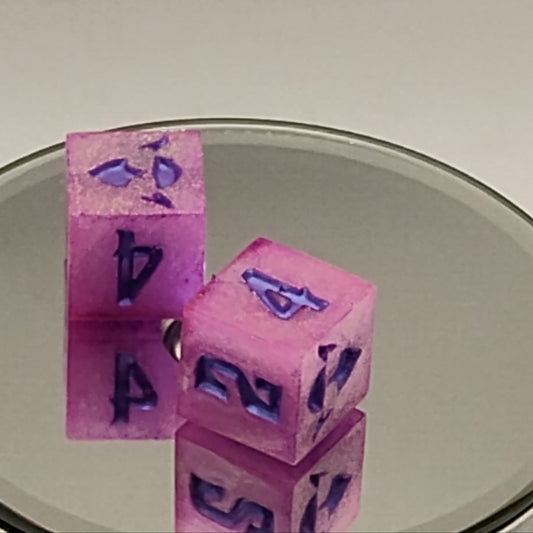 Pink dice with blue numbers on a reflective surface