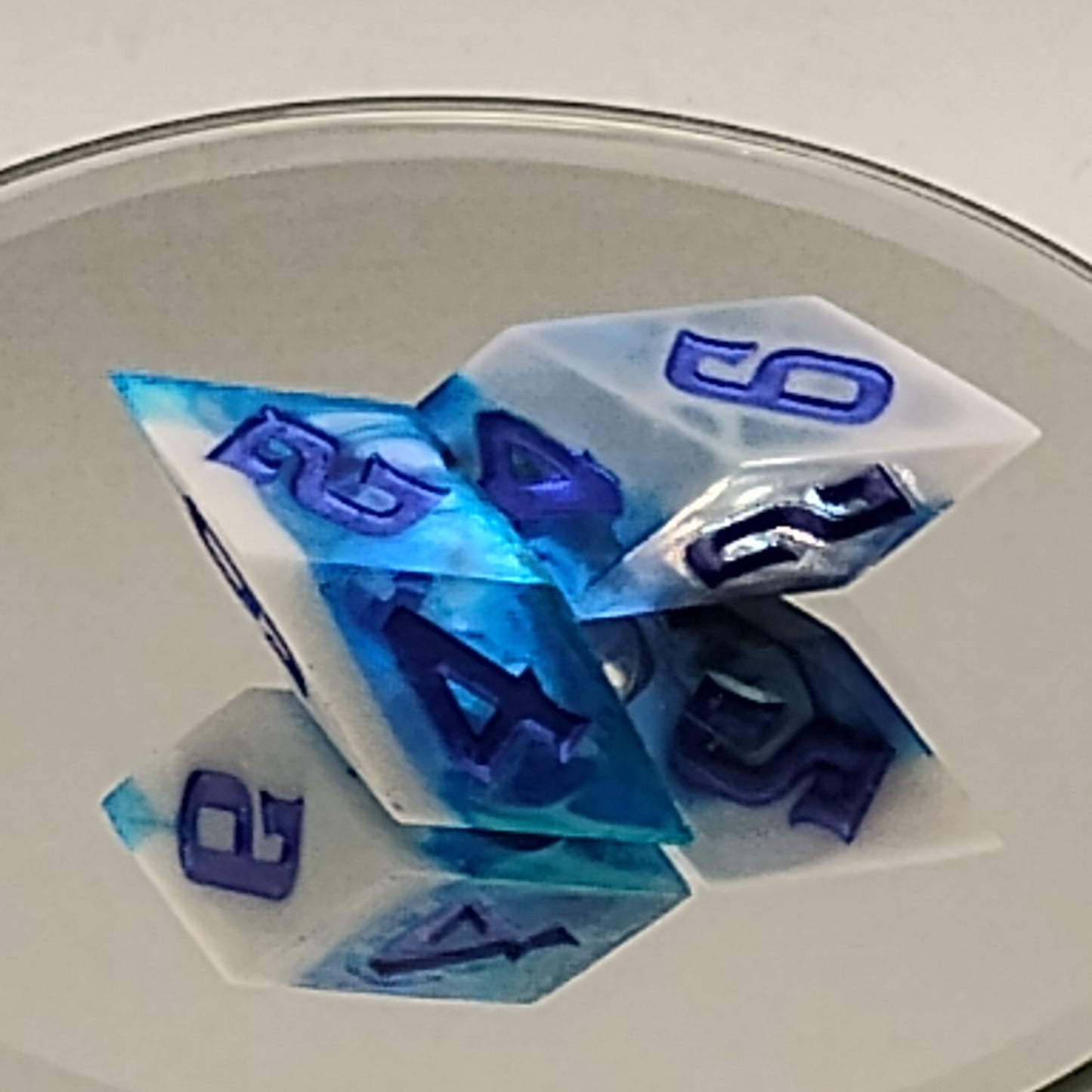 Set of polyhedral dice with blue and white numbers on a reflective surface