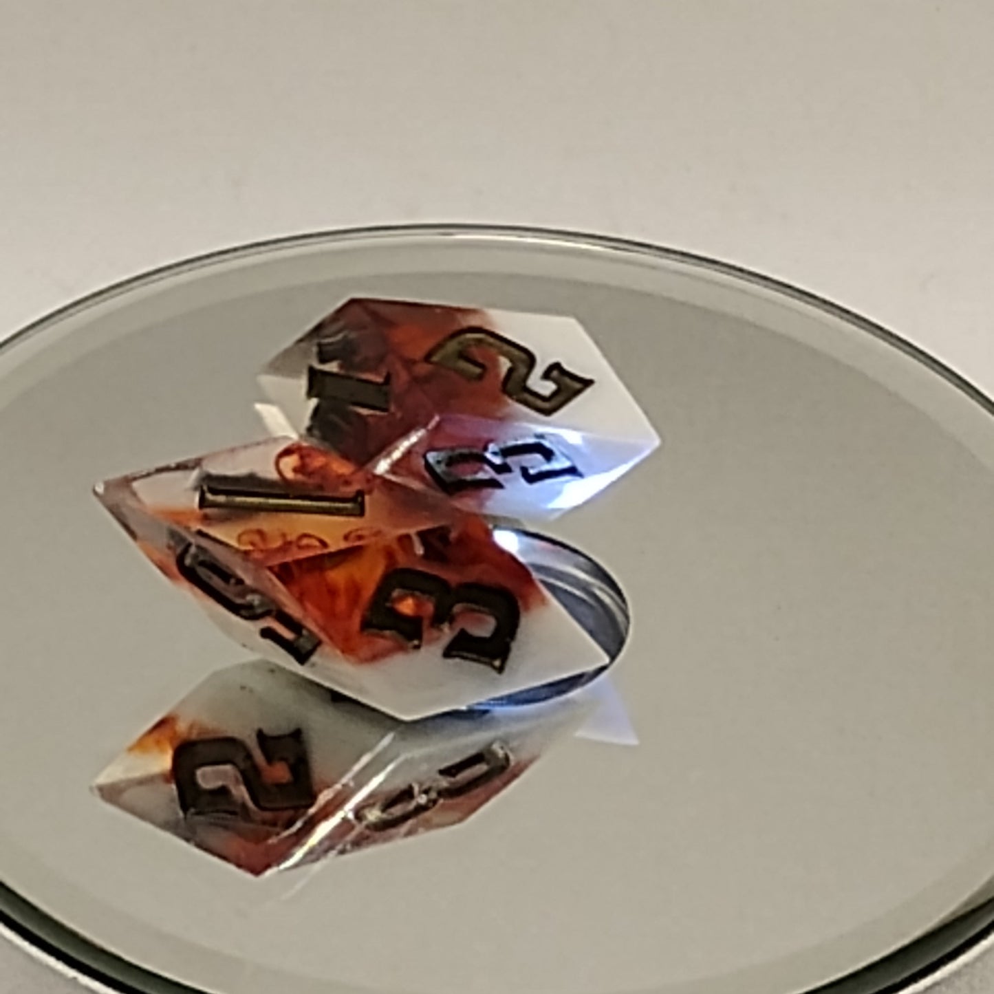 Two dice with black and orange numbers on a reflective surface