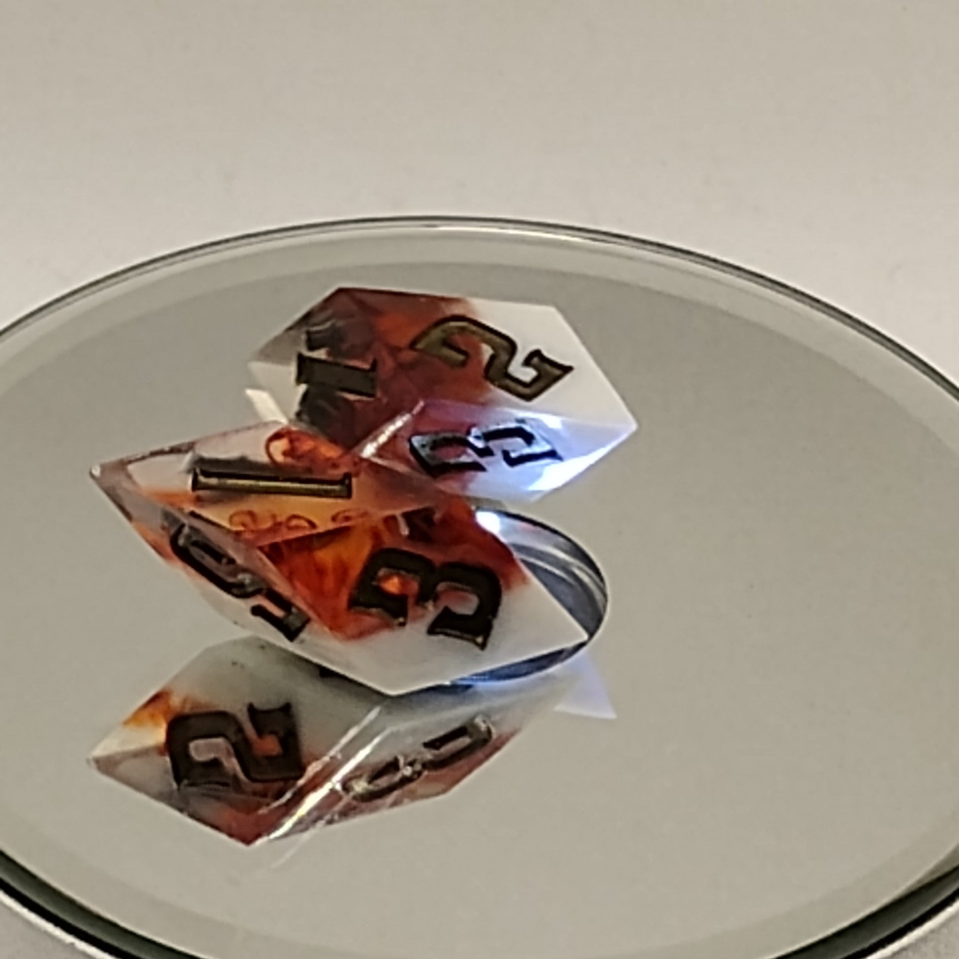 Two dice with black and orange numbers on a reflective surface