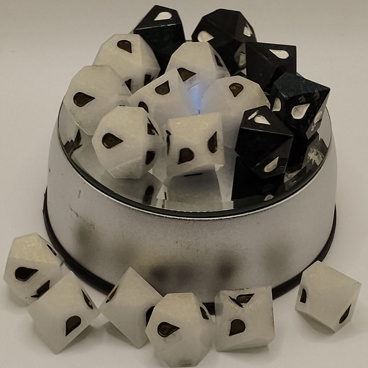 Set of black and white dice with a metallic container on a light gray background