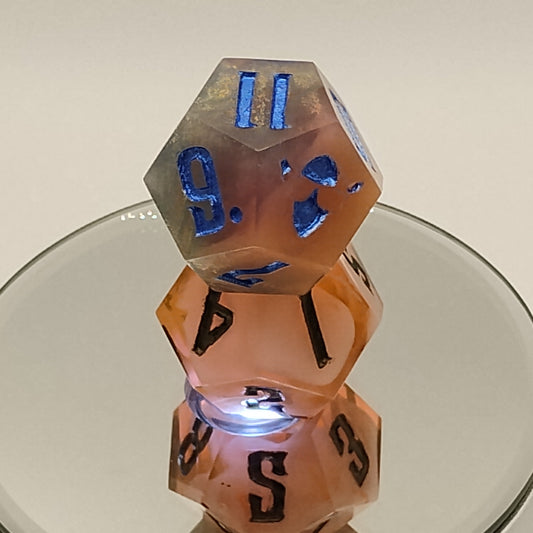 Two polyhedral dice with blue and black numbers on a reflective surface.