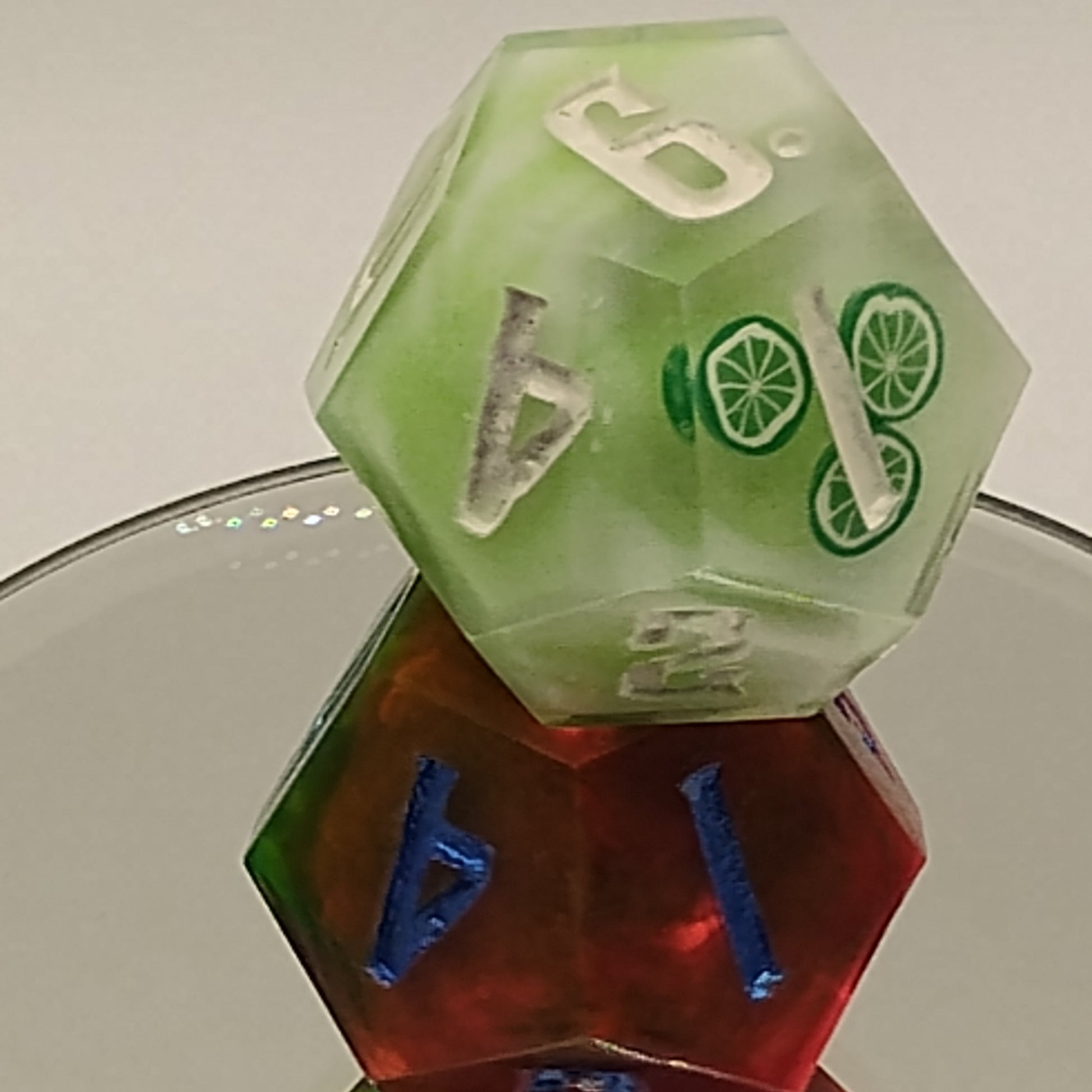 Close-up of green and red polyhedral dice on a reflective surface