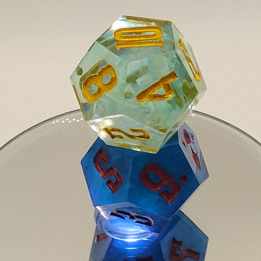 Two polyhedral dice, one green with yellow numbers and one blue with red numbers, held together by a clear plastic hoop.
