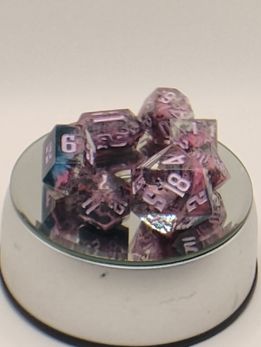 A set of translucent purple polyhedral gaming dice with white numbering, displayed on a small mirrored tray against a plain light background.
